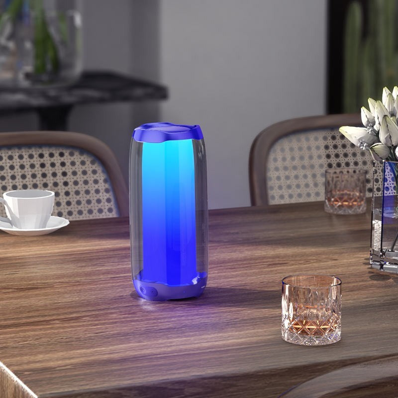 OBtech Hoco HC8 portable wireless Bluetooth speaker with vibrant blue pulsating RGB lighting on a wooden dining table.
