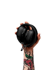 OBtech Marshall Major IV wireless headphones held in a tattooed hand against a black background